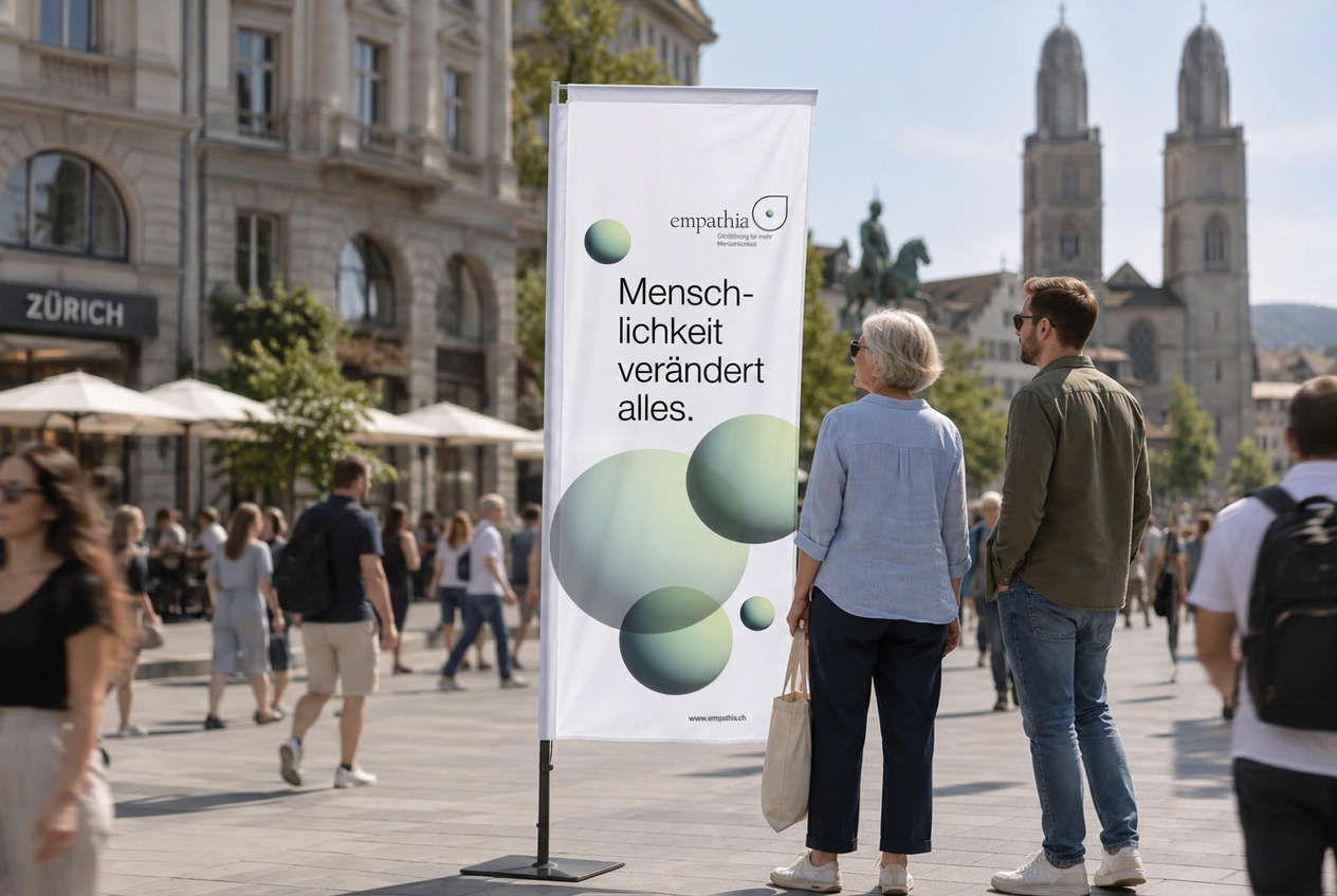 Empathia Beach Flag mit dem Sujet «Menschlichkeit verändert alles.» auf einem belebten Platz